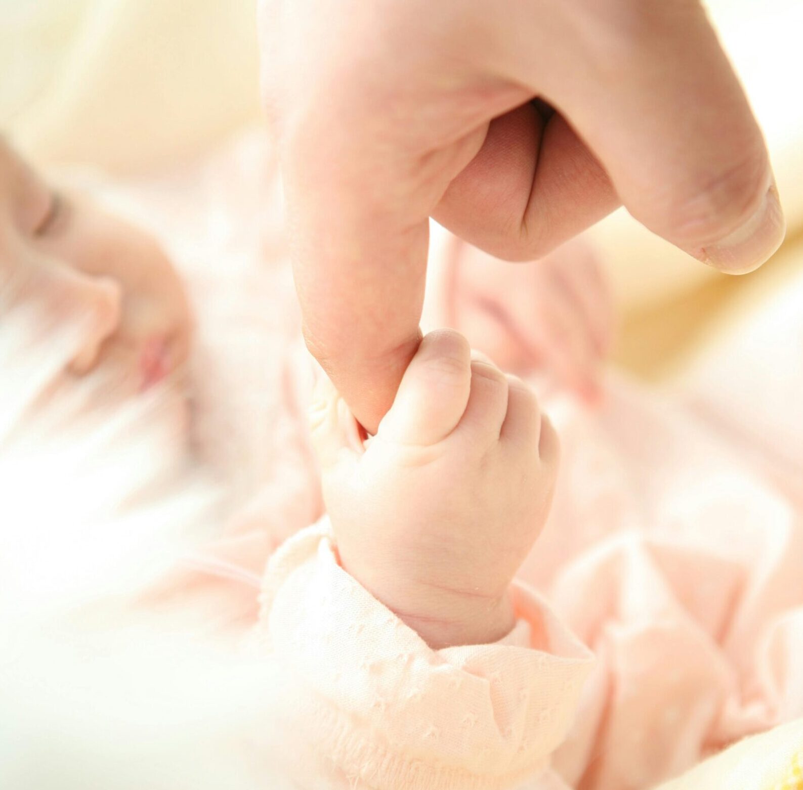 「新生児が大人の指を握る、無垢でやさしい手のひらのクローズアップ」
